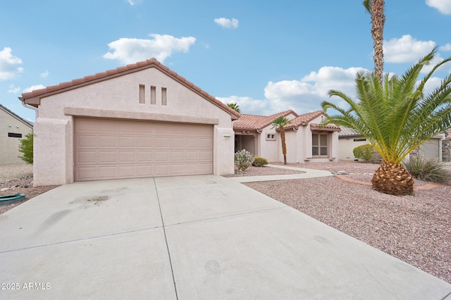 mediterranean / spanish home featuring a tile roof, stucco siding, an attached garage, and concrete driveway