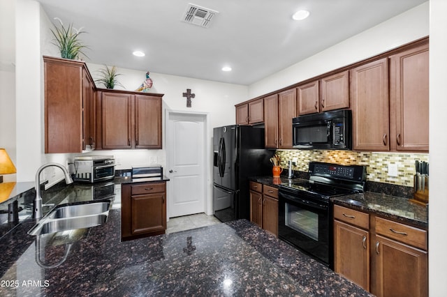 kitchen with a sink, visible vents, backsplash, black appliances, and dark stone countertops