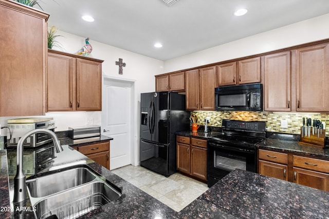 kitchen with recessed lighting, a sink, decorative backsplash, black appliances, and dark stone countertops