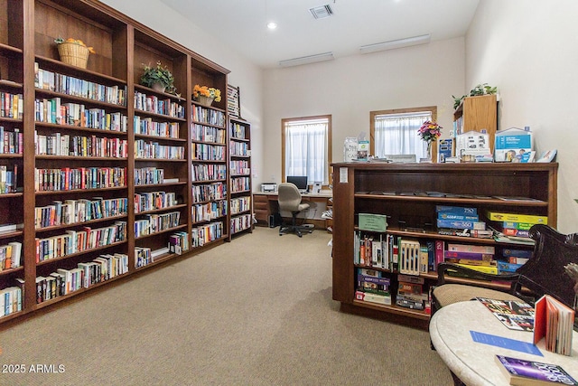 sitting room featuring visible vents, bookshelves, and carpet flooring