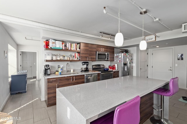 kitchen with a kitchen bar, appliances with stainless steel finishes, a center island, pendant lighting, and sink