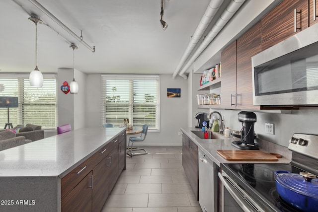 kitchen with rail lighting, appliances with stainless steel finishes, sink, hanging light fixtures, and a center island