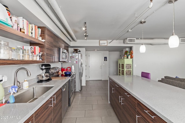 kitchen featuring appliances with stainless steel finishes, track lighting, decorative light fixtures, sink, and dark brown cabinets