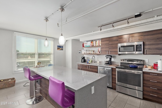 kitchen with appliances with stainless steel finishes, a center island, a kitchen breakfast bar, sink, and light tile patterned flooring