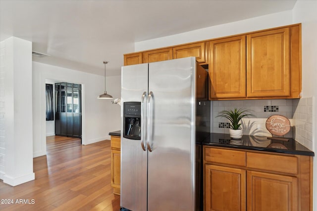 kitchen with hanging light fixtures, stainless steel refrigerator with ice dispenser, decorative backsplash, and wood-type flooring