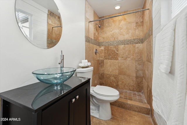 bathroom featuring a tile shower, tile patterned floors, vanity, and toilet