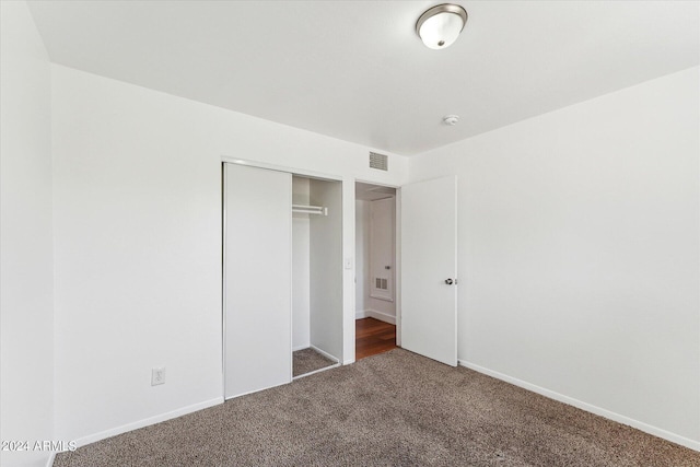 unfurnished bedroom with dark carpet and a closet