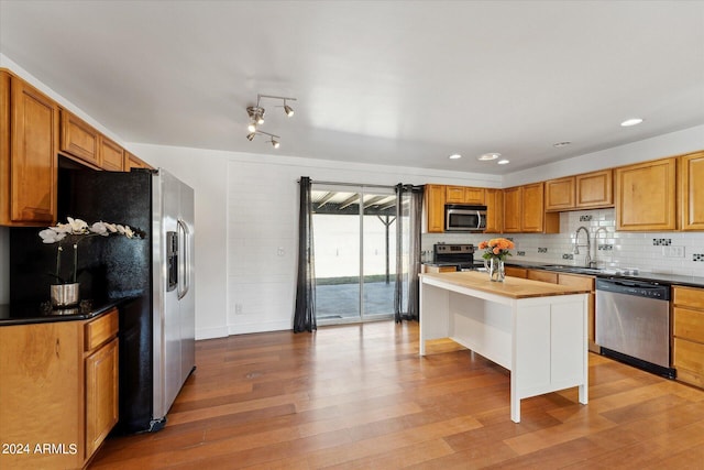 kitchen featuring sink, tasteful backsplash, stainless steel appliances, a center island, and light hardwood / wood-style floors