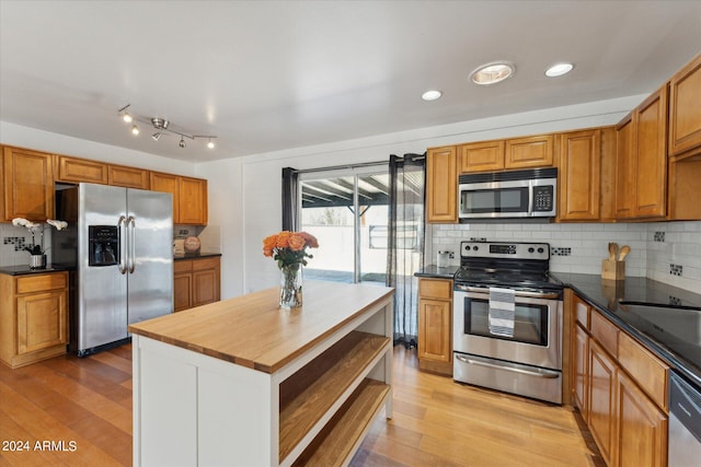 kitchen featuring decorative backsplash, stainless steel appliances, wooden counters, a center island, and light hardwood / wood-style flooring