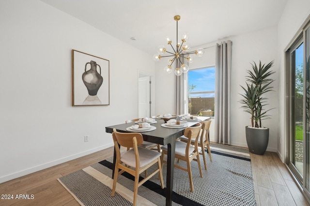 dining room with a wealth of natural light, light hardwood / wood-style flooring, and an inviting chandelier