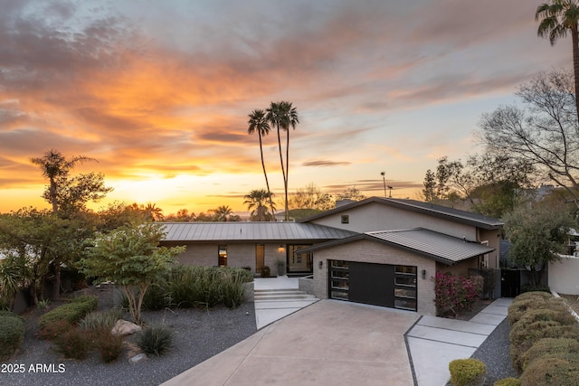 view of front of property featuring a standing seam roof, metal roof, concrete driveway, and an attached garage