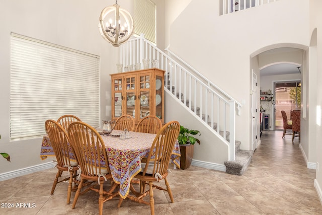 dining area featuring a notable chandelier, a towering ceiling, and light tile patterned floors