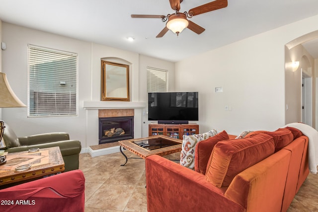 living room with a tiled fireplace, light tile patterned floors, and ceiling fan