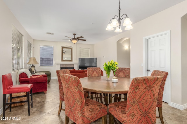 tiled dining space featuring ceiling fan with notable chandelier