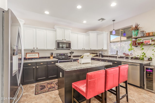 kitchen with beverage cooler, a center island, stainless steel appliances, pendant lighting, and white cabinets