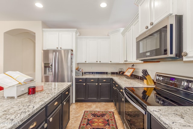 kitchen featuring light stone counters, stainless steel appliances, light tile patterned floors, and white cabinets