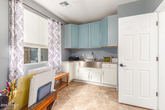 kitchen featuring blue cabinets, sink, and light tile patterned flooring