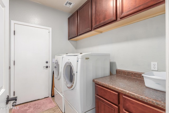 clothes washing area featuring washer and dryer, cabinets, and light tile patterned floors