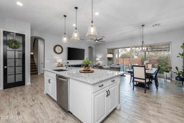 kitchen with dishwasher, white cabinets, a center island with sink, and sink