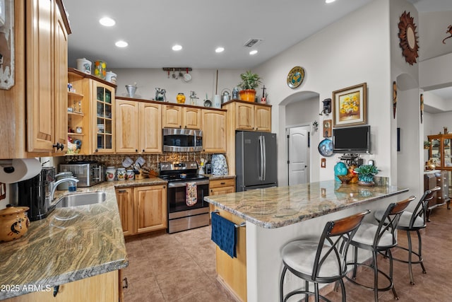 kitchen with visible vents, a kitchen breakfast bar, stainless steel appliances, arched walkways, and dark stone counters
