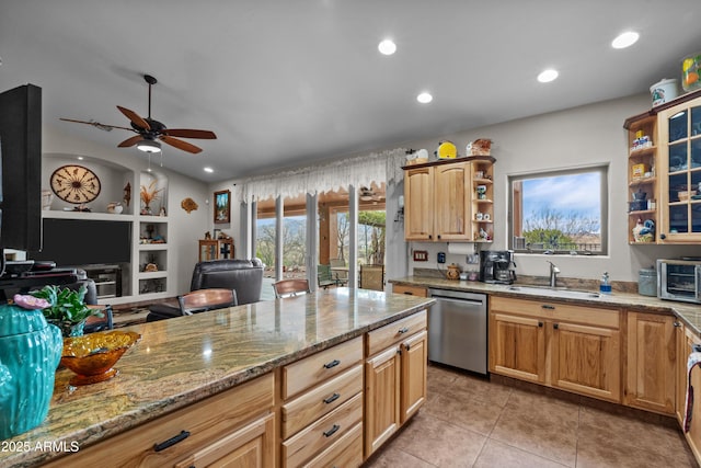 kitchen featuring a ceiling fan, open shelves, light stone counters, a sink, and stainless steel dishwasher