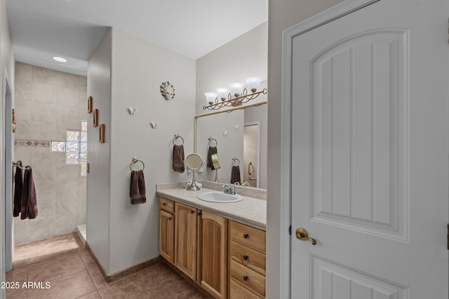 bathroom with tile patterned flooring, baseboards, vanity, and a tile shower