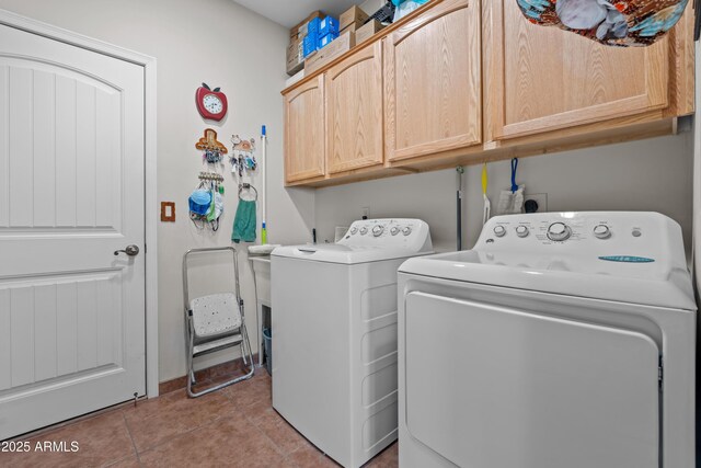 clothes washing area featuring washer and dryer, light tile patterned flooring, and cabinet space