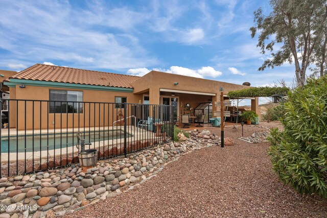 back of property with stucco siding, a patio, a fenced in pool, and fence