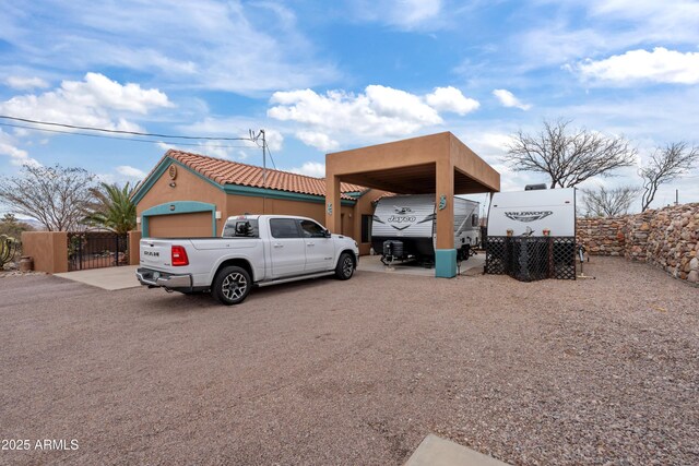 exterior space with a detached carport, a gate, and stucco siding
