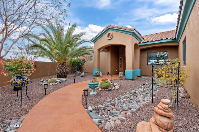 property entrance featuring a patio area, a tile roof, stucco siding, and fence