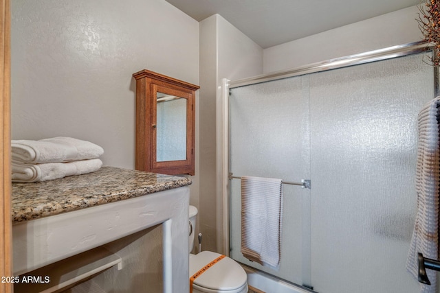 bathroom featuring vanity, toilet, and an enclosed shower