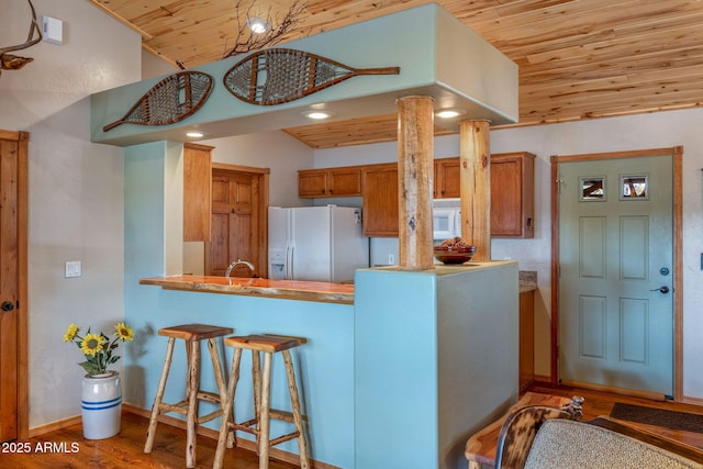 kitchen featuring wood ceiling, wood-type flooring, a kitchen breakfast bar, kitchen peninsula, and white appliances