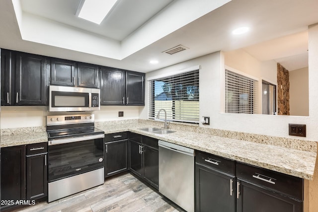 kitchen with light stone countertops, sink, and stainless steel appliances