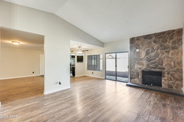 unfurnished living room with ceiling fan, lofted ceiling, a fireplace, and hardwood / wood-style floors