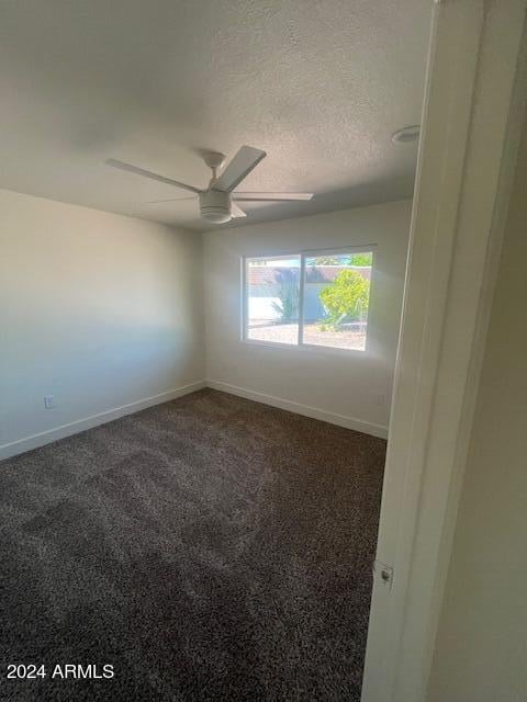 carpeted empty room featuring ceiling fan and a textured ceiling