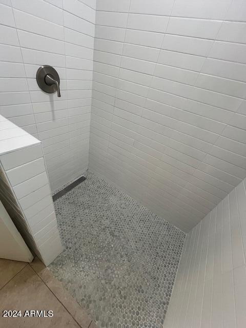 bathroom with a tile shower and tile patterned floors