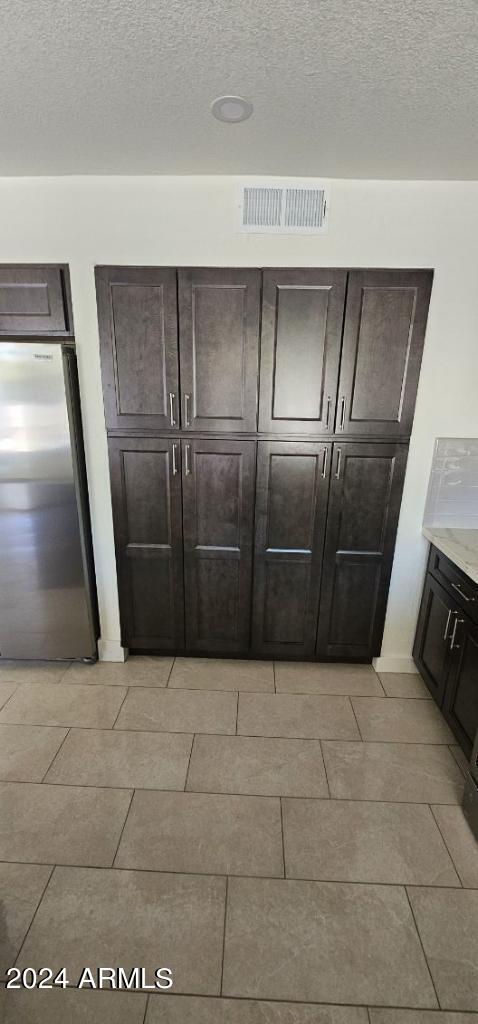 details featuring stainless steel fridge, tile patterned floors, and a textured ceiling