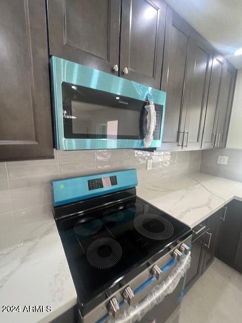 kitchen featuring tasteful backsplash, dark brown cabinets, black electric range oven, and light stone countertops