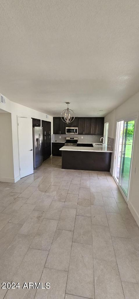 kitchen featuring stainless steel appliances, kitchen peninsula, an inviting chandelier, and a textured ceiling