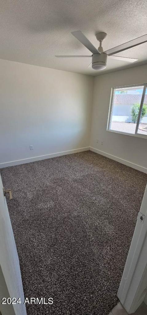 empty room featuring ceiling fan, carpet floors, and a textured ceiling