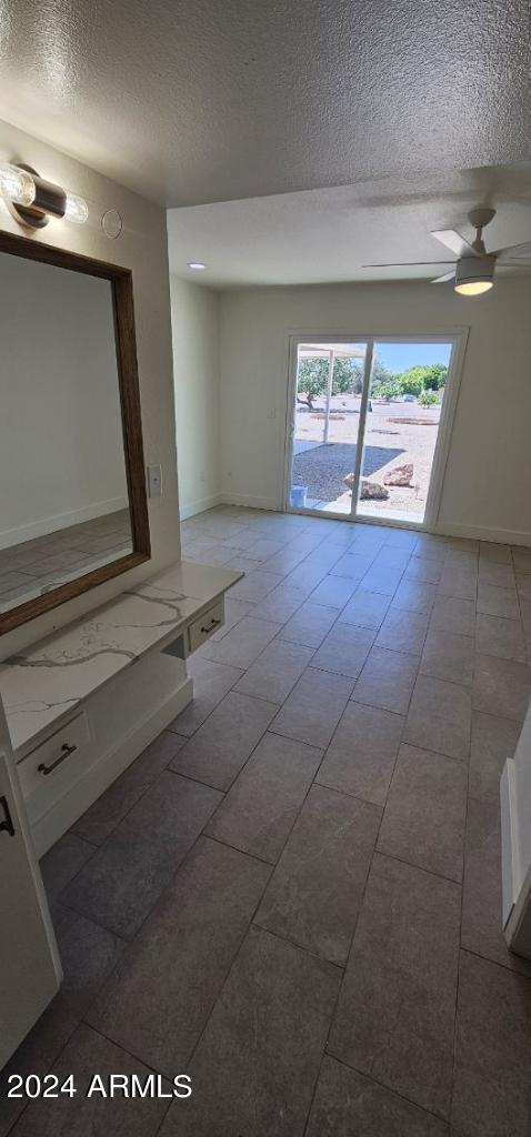 empty room featuring dark tile patterned floors, ceiling fan, and a textured ceiling