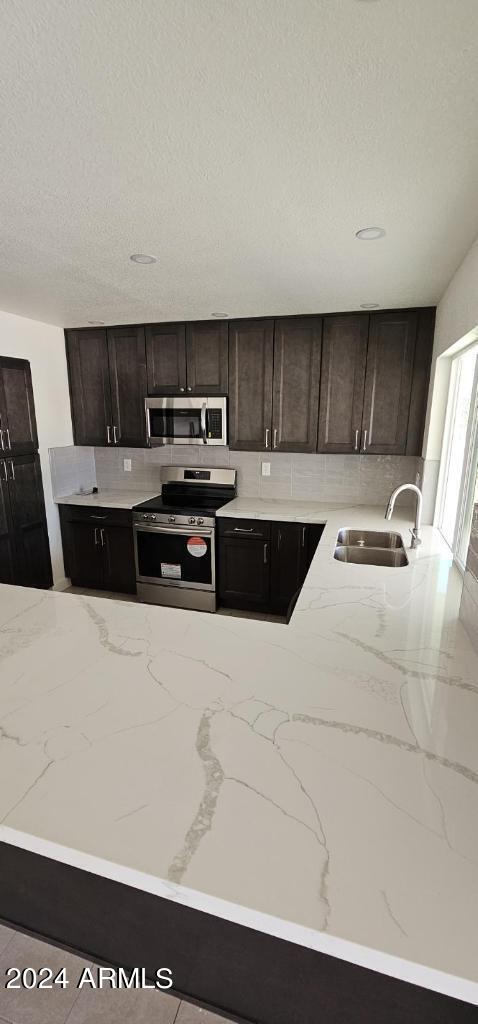 kitchen with stainless steel appliances, dark brown cabinetry, sink, and a textured ceiling