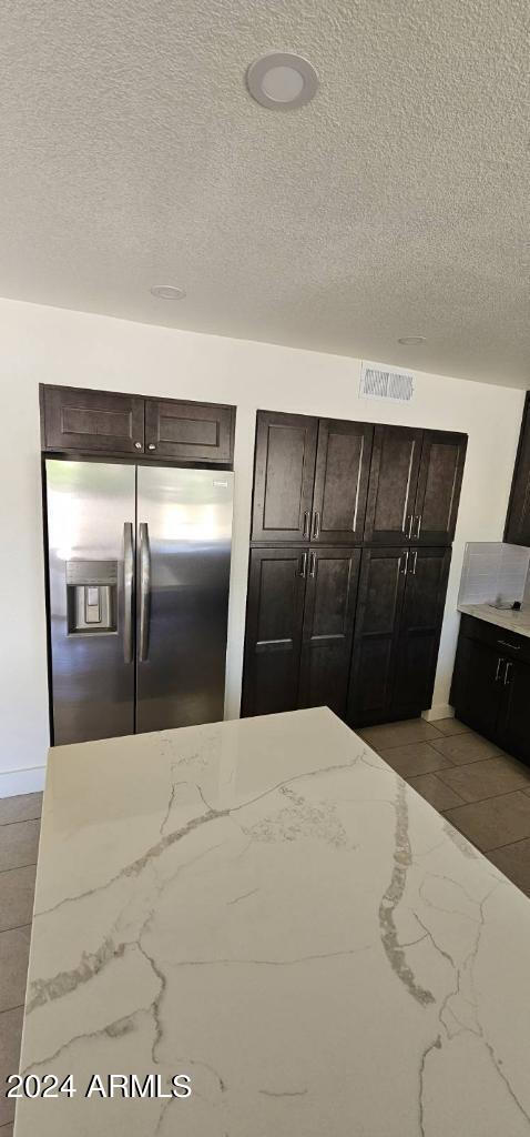 unfurnished bedroom with a textured ceiling and stainless steel fridge with ice dispenser