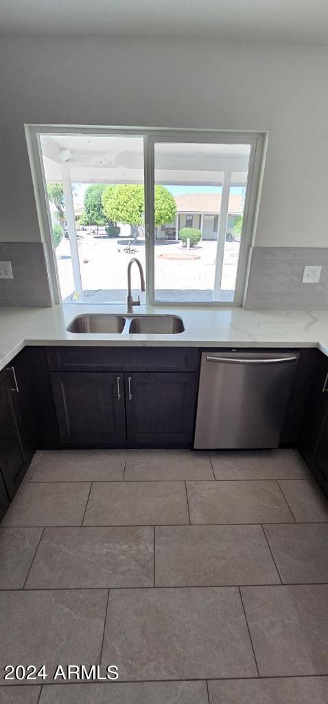 kitchen with light tile patterned flooring, sink, stainless steel dishwasher, and a healthy amount of sunlight