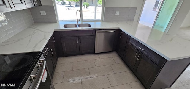 kitchen featuring light stone counters, sink, stainless steel appliances, and tasteful backsplash