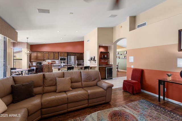 3797 N 156th Dr N, Goodyear, AZ 85395 - living room with visible vents, beverage cooler, dark wood-style floors, high vaulted ceiling, and arched walkways