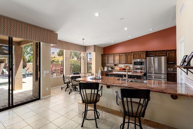 3797 N 156th Dr N, Goodyear, AZ 85395 - kitchen with dark stone counters, appliances with stainless steel finishes, a kitchen breakfast bar, and visible vents
