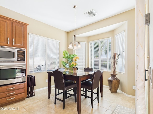 dining room featuring light tile patterned floors, visible vents, a chandelier, and baseboards