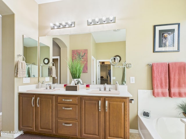 bathroom featuring double vanity, a garden tub, and a sink