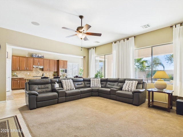 living area with visible vents, light colored carpet, and a ceiling fan